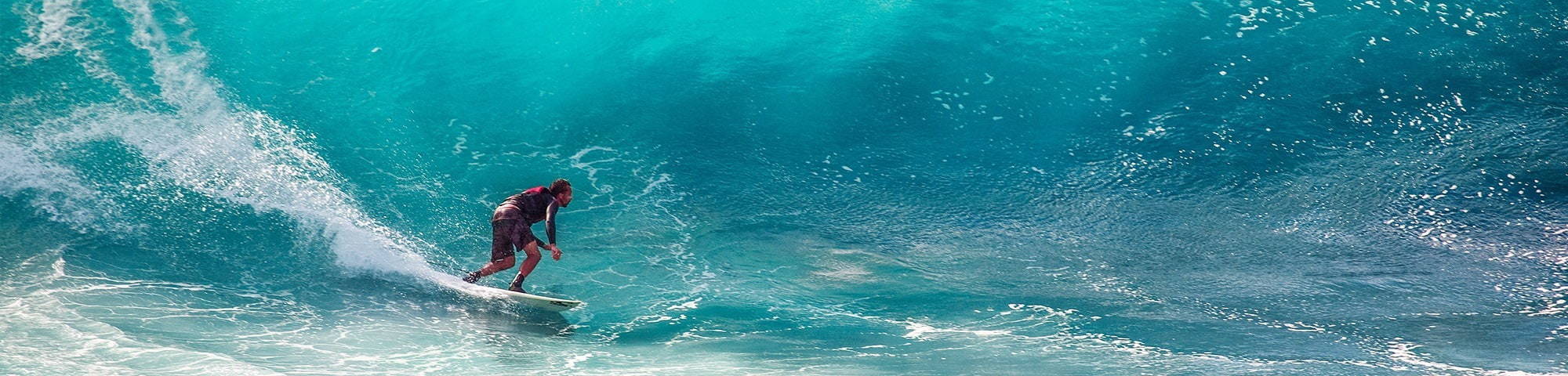 Male surfing waves in clear blue sea